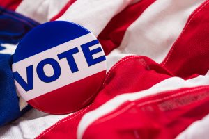 A "VOTE" pin or button on a flag of the United States