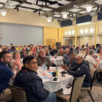 Large room of people seated at round tables