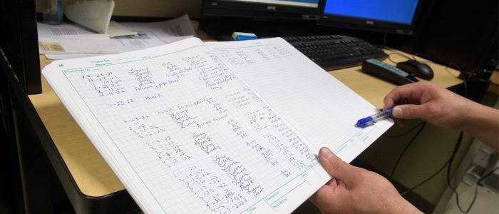 close-up of a hand holding research notes on top of a desk