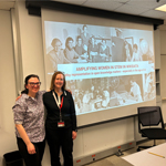 Two people stand in front of a presentation screen
