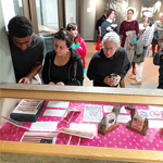 Three people look down at a display case.