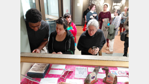 Three people look down at objects in a display case.