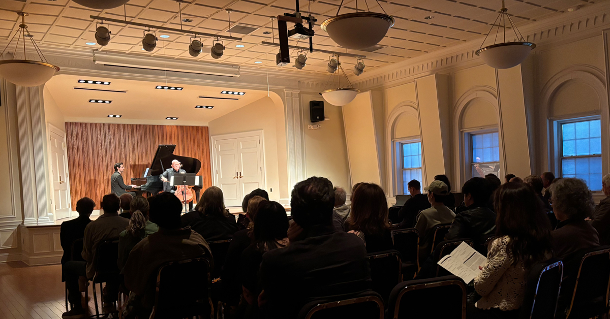 View from behind of a darkened audience, with a musical performance taking place onstage