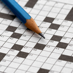 Close-up of a pencil lying on top of a blank crossword puzzle