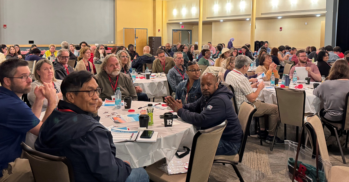A large room full of people seated at round tables