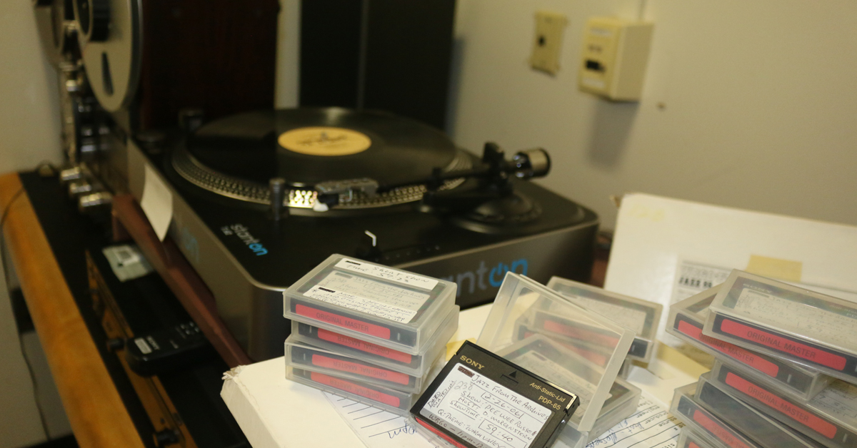 Audio reels and digital audiotapes lying on a table in front of a record player