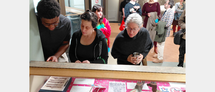 America's Birthdays meta 1280x720 Three people look down at objects in a display case.