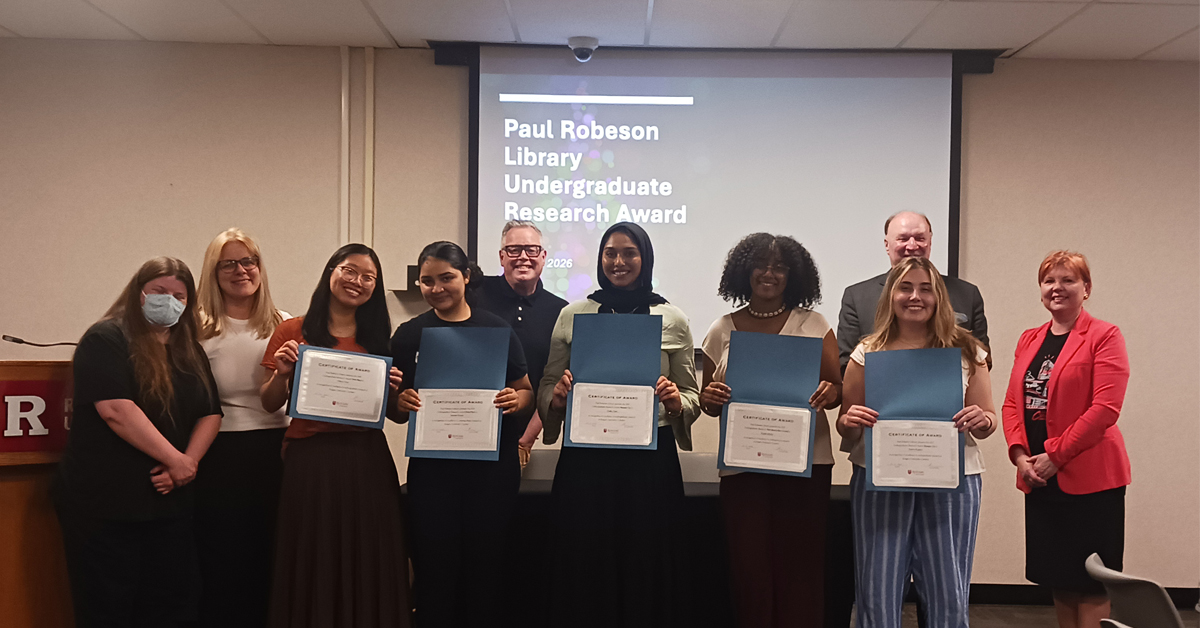 A group of people poses, smiling, with five people in the middle holding certificates.